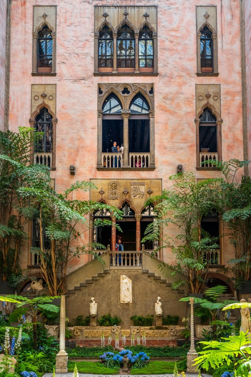 Interior courtyard of the Isabella Stewart Gardner Museum with flowering plants and Venetian architecture