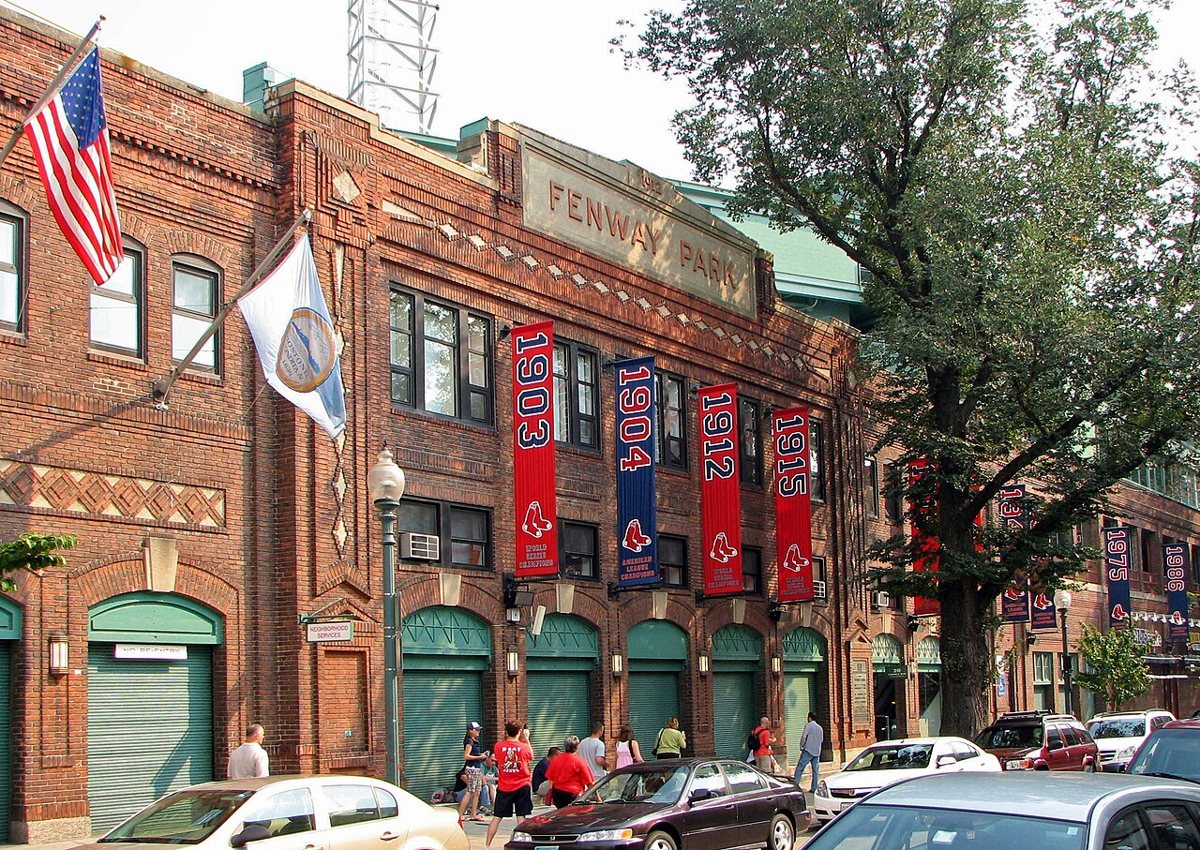 Night game at Fenway Park with the Green Monster in left field lit up under stadium lights