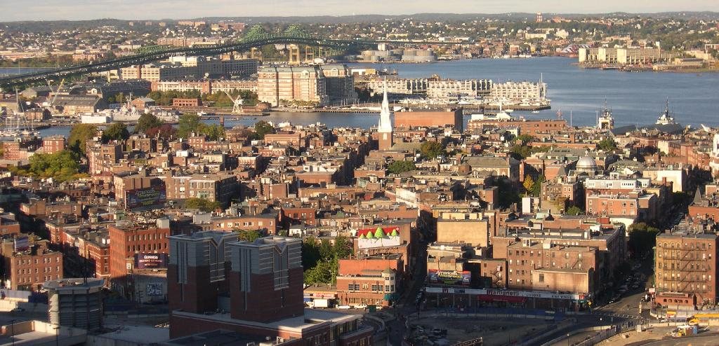 Narrow brick-paved street in Boston's North End neighborhood with Italian bakeries and street life