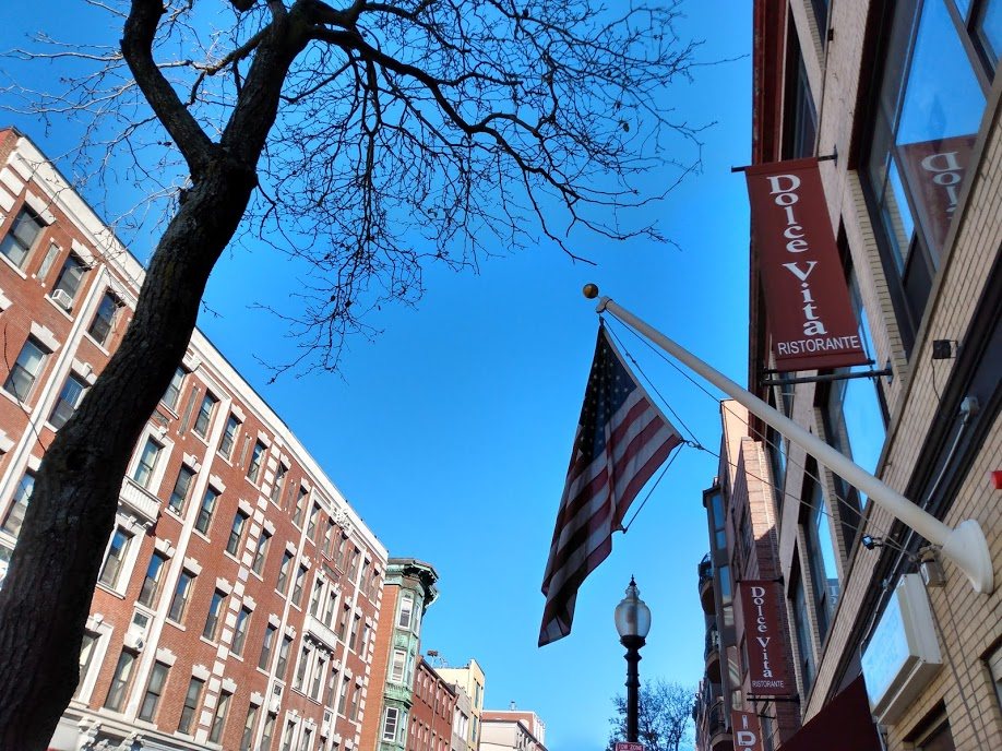 outdoor cafe tables and Italian bakery windows along Hanover Street in the North End